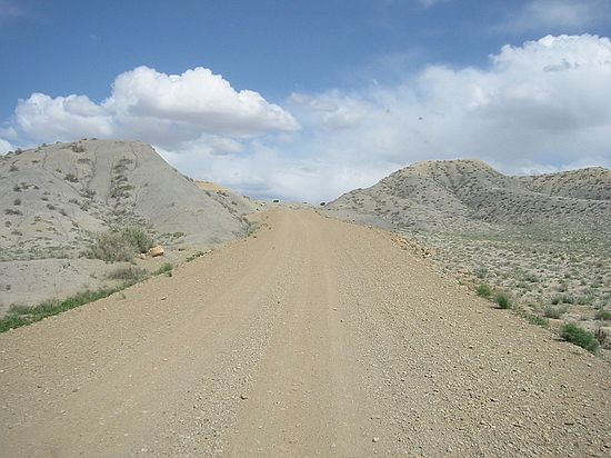 Contrast of grey Mancos Shale with tan dirt road.