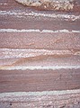 Fountain formation: alternating layers of dark red and white are differing iron content.  The white (or light) areas are more permeable and the iron has been leached out and reduced, leaving a lighter colored material.  The dark red areas more muddy and are far less permeable.  They still contain high levels of iron oxides.  Note that these are not the original color of the rock.  It is all the result of weathering and water intrusion.