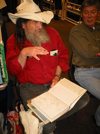 Bob Bakker imitating a dinosaur while signing his book.  Interesting attire - a cross between Willie Nelson (long hair), a cowboy, and an engineer (15 pens in pockets)!!!